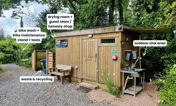 A wooden cabin in the trees with sink and facilities with name labels
